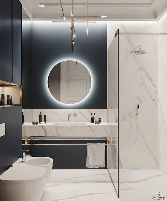 White marble vanity with an illuminated oval mirror and brass fixtures